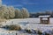 Snow-covered field with forest and fodder rack