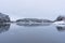 Snow-covered forest against the background of the unfrozen sea, rocky coast. Snowy winter concept. Finnish nature.