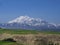 Snow covered huge mountain Elbrus on horizon against the blue sky.