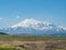 Snow covered huge mountain Elbrus on horizon against the blue sky.