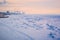 Snow-covered ice of the Amur River on a winter morning. Cranes of the river port in the background