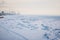 Snow-covered ice of the Amur River on a winter morning. Cranes of the river port in the background.