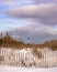 Snow covered landscape leading to a lighthouse under wispy clouds. Fire Island, New York.