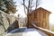 A snow covered lane with a building and walls on either side,, and glimpses of a distant town