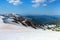 From the snow covered lawn opens a view of high mountains with snow covered tops, blue sky. Magnificent spring landscape.