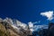 Snow-covered majestic mountain peaks with dark blue sky and flowing clouds.