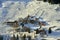 Snow-covered mountain village on sun-drenched hill slope in sunny winter afternoon, Ischgl Tyrol Alps