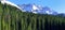 Snow covered mountains in the back of green conifer forest