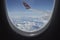 Snow covered mountains and clouds seen through window of an aircraft.