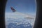 Snow covered mountains and clouds seen through window of an aircraft.