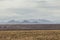 Snow covered mountains and open plains of a wide open desert vista landscape on overcast day