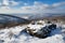 snow-covered mountaintop, with view of rolling hills and valleys below