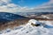 snow-covered mountaintop, with view of rolling hills and valleys below