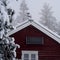 Snow-covered Norwegian off-grid cabin with solar panel in snowy weather