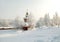 Snow covered orthodox chapel amidst winter grove on the background of hoary forest