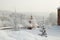 Snow covered orthodox chapel with brick fence at winter on the background of hoary forest