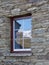 Snow covered range reflected in historic stone cottage window, New Zealand