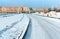 Snow-covered road to the city, road junction overpass and high-rise buildings in the winter in the snow