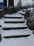 Snow covered stair steps without handrails for pedestrians with rocks and stones