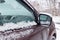 Snow covered SUV side mirror closeup. Cars in winter