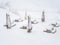 Snow-covered tables with benches and folded outdoor umbrellas stand on the site on a winter day during a blizzard