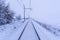 Snow covered train tracks leading into a thick fog