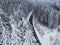 Snow-covered trees in the forest and blue car on the road line in the mountains