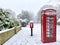 Snow covered village post box and phone box