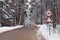 Snow-covered winter road in a pine forest and a lone traveler