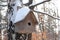 Snow covered wooden birdhouse in a winter forest. a birdhouse in the woods in winter