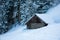 Snow covered wooden cottage in alpine forest