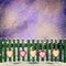 Snow-covered wooden fence with hanging on it with paper hearts