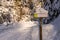 Snow-covered wooden road sign with warning text in German and English: Mountain bikers Please slow down.