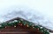 Snow covered wooden roof with hanging spruce branches and colorful new year Christmas toys and decorations. Natural winter backgro