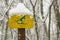 Snow-covered yellow sign with a skier on the ski track