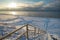 Snow Curonian Spit dunes in January winter sunny day. Blue sky and sea, no people on the beach, wooden stairway, calm