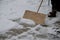 A snow disaster has covered places where snow is a rarity. girl clears the snow structure using the home method. wooden shovel in