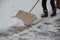 A snow disaster has covered places where snow is a rarity. girl clears the snow structure using the home method. wooden shovel in