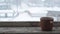 Snow falling on a cup on old wooden window sill