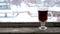 Snow falling on glass cup on old wooden window sill