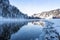 Snow forest on Bank of winter river. Reflection of frost trees