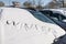 Snow on a front shield of a car with the word winter