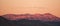 Snow geese flying across mountain top at sunrise.