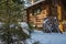 Snow on green pine tree with wooden cabin in snow