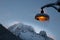 Snow and icicle covered amber lightpost against backdrop of wind