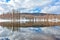 Snow and lake, lake surrounded by snow and trees, reflection of trees and clouds sky and snow-covered mountains on a lake in winte