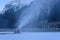 Snow-machine bursting artificial snow over a skiing slope