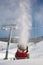 Snow-machine bursting artificial snow over a skiing slope