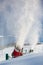 Snow-machine bursting artificial snow over a skiing slope