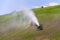 Snow making machines used to water grass on slope, sunny summer day, Wagrain ski resort